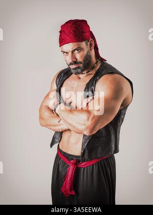 Serious bearded man in genie costume crossing arms and looking at camera against gray background Stock Photo