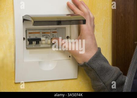 Close up of male hand using an electronic control panel, to switch on electricity at home Stock Photo