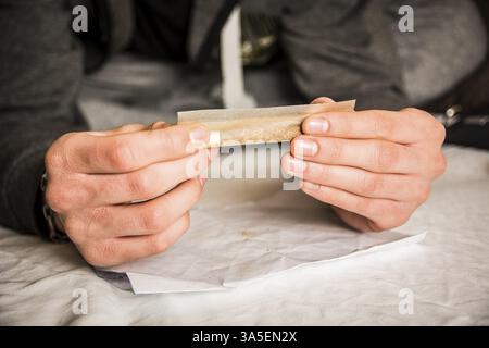 Close-up of young man', s hands rolling cigarette. Unrecognizable Stock Photo