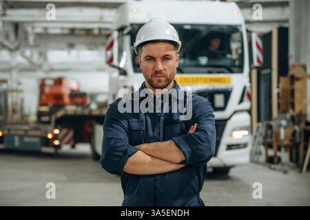 Standing in front of a truck. Male worker is in the modern warehouse or manufacturing company. Stock Photo