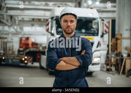 Standing in front of a truck. Male worker is in the modern warehouse or manufacturing company. Stock Photo