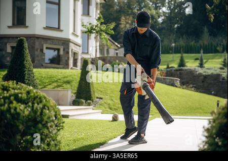 Using leaf blower. Professional gardener is on the lawn. Stock Photo