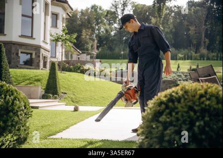 Using leaf blower. Professional gardener is on the lawn. Stock Photo