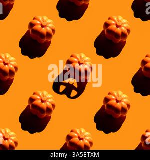 Small orange pumpkins arranged in a diagonal pattern on a flat orange background, casting shadows, autumnal concept. seamless pattern Stock Photo