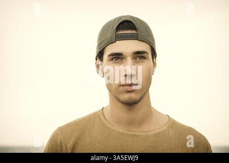 Portrait of handsome young man outside wearing baseball cap, looking at camera. Head and shoulders shot Stock Photo