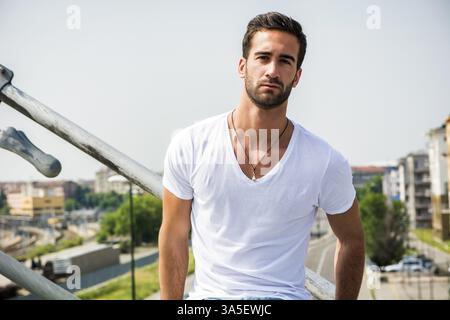 Handsome bearded young man outdoors in urban environment looking at camera Stock Photo