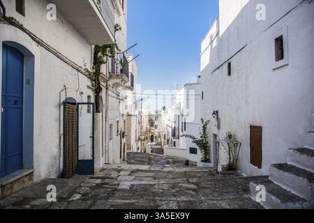 Narrow Cobblestone Alley Between White Washed Mediterranean Houses on Hill Side in Ibiza, Spain on Sunny Day with Blue Sky Stock Photo