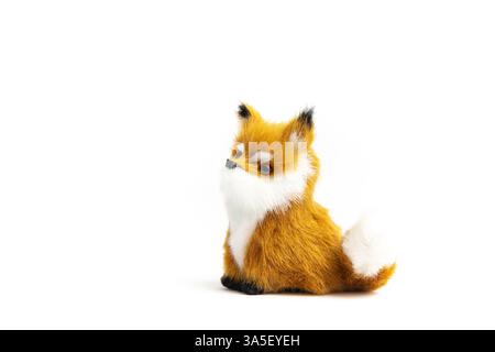 A small, plush fox toy sits against a white background. It has orange and white fur and a black nose. Stock Photo