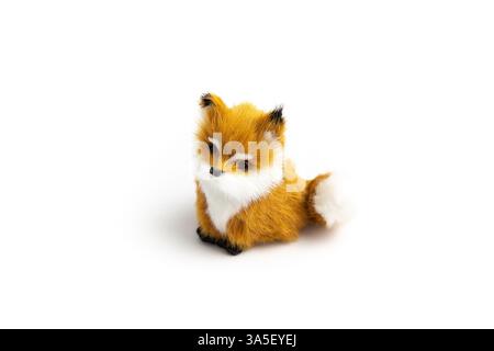 A small, plush fox toy sits against a white background. It has orange and white fur and a black nose. Stock Photo