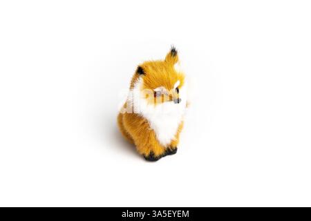 A small, plush fox toy sits against a white background. It has orange and white fur and a black nose. Stock Photo