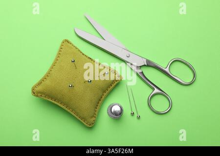 Different sewing supplies on green background, flat lay Stock Photo