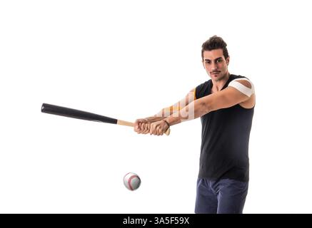 Adult man with Kinesio tapes on arms holding baseball bat and hitting ball away on white background Stock Photo