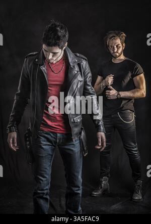 Two attractive young hard rock men posing in studio. Black background Stock Photo