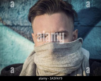 A man with a scarf around his neck, hiding his nose and mouth Stock Photo