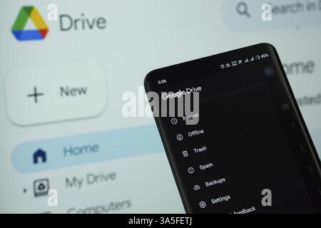 The app of the google drive is displayed on a smartphone screen, and the website google drive is visible on a computer screen in the background Stock Photo
