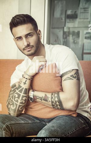 Handsome man sitting on couch looking at camera Stock Photo