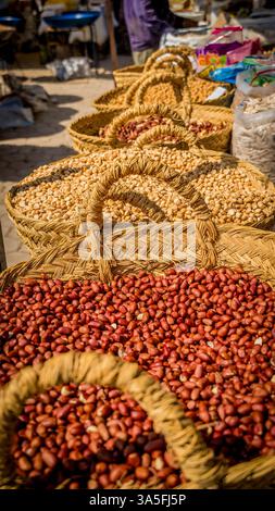 Market scene with colorful displays of spices, woven baskets, and almonds, pistachios, and walnuts, in Tunisia Stock Photo