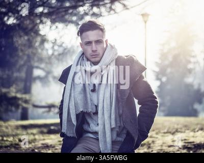 One handsome blue eyed young man in urban setting in European city park Stock Photo