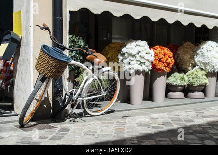White bike with wicker basket on italian street. Many Pots with flowers on background. Sunny day. Typical italian style Stock Photo