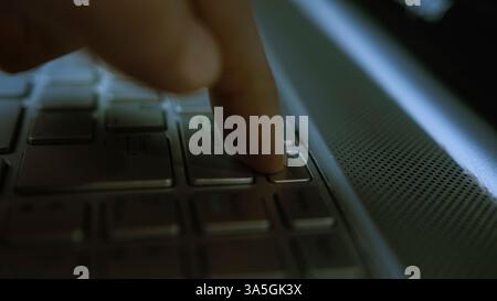 Close-up of a Finger Pressing the Delete Key on a Laptop Keyboard in Low Light Stock Photo
