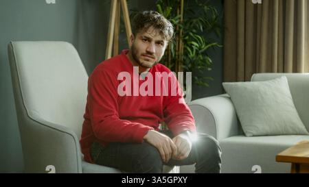 Young Man Sitting in a Cozy Living Room, Looking Warm and Friendly Stock Photo