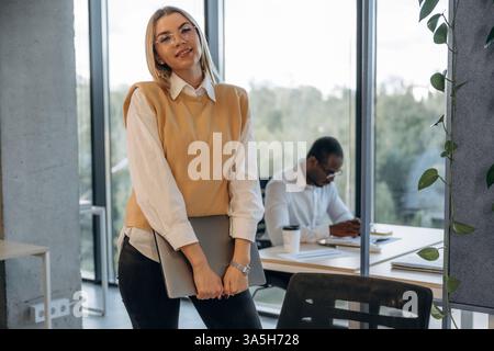 Standing in front of her colleague. Two business people are working together in the office. Stock Photo