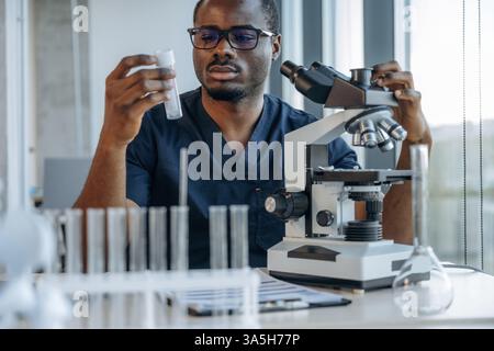 Bunch of test tubes. Scientist is working indoors, microscope is on the table. Stock Photo