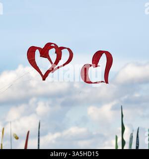 Three red heart-shaped kites flying in the sky, text free space, kite festival in Vinsebeck, Steinheim, Eggegebirge nature park Park and southern Teut Stock Photo