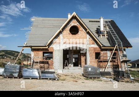 Laying roof tiles on new build house Stock Photo