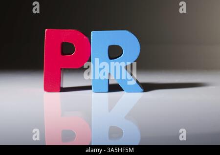Multicolored text PR made of wood. White background Stock Photo