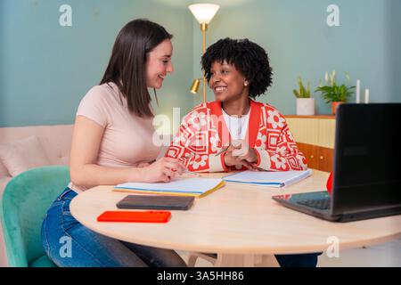 Two multiethnic young female friends studying together using laptop at home Stock Photo