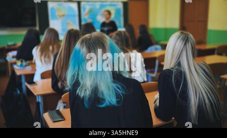 Students in a classroom listening to their teacher explain a geography lesson while sitting at their desks Stock Photo