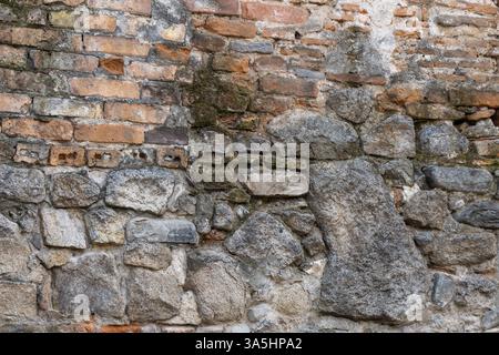 This captivating wall features a blend of old bricks and rugged stones, each telling a story of time and craftsmanship. Nature and history converge in Stock Photo