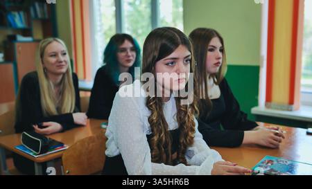 Focused high school female students engaged in classroom lesson with teacher Stock Photo