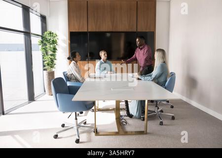 Engaged young team participate briefing or training led by African boss, coach or trainer stand in front of staff members, make speech, presenting new Stock Photo
