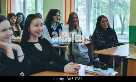 Students attentively listening to teacher during classroom lesson at school Stock Photo