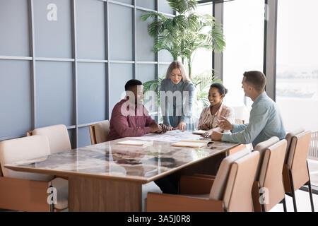 Group of professionals discussing strategy, working collaboratively on project gathered together in modern conference room. Multiethnic shareholders r Stock Photo