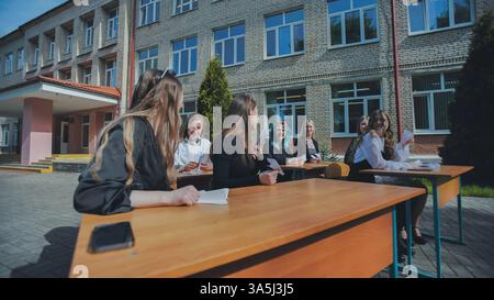 High school students are taking an exam at desks outside in the fresh air, enjoying a unique learning environment Stock Photo