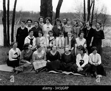 A group portrait of women from the Tholia Literary Society at St. Cloud State University, captured with some standing and others seated. The photo features a river in the background. Stock Photo