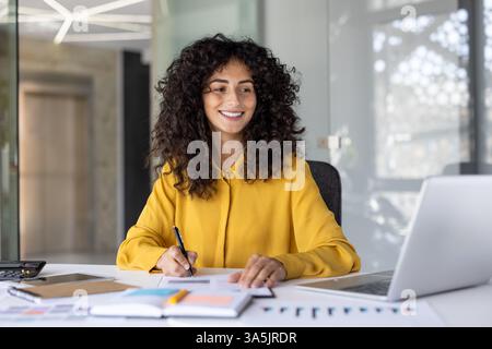 Successful businesswoman financier doing paperwork inside office. Woman with documents and papers, satisfied with financial results smiling. Accountant preparing report and filling in data. Stock Photo