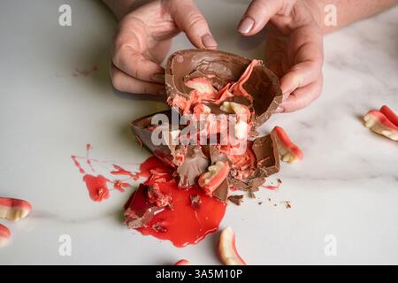 Confectionershowing children's strawberry and raspberry filling in chocolate Easter egg. Stock Photo