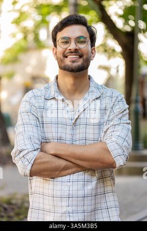 Portrait of happy smiling Indian young man looking at camera, resting, relaxation feel satisfied glad expression of good news outdoors. Hispanic guy tourist on urban city street. Town lifestyles. Stock Photo