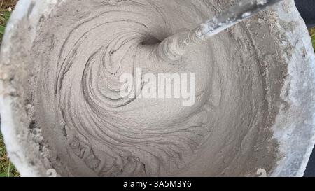 Construction worker mixing cement in bucket using mixing drill Stock Photo