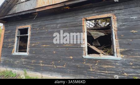 Burnt wooden house with broken windows showing charred remains of roof and interior Stock Photo