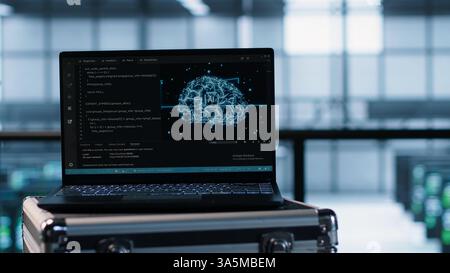 Laptop in front of data center engineers in blurry background deploying artificial intelligence driven management tools. AI driven notebook used for overseeing server clusters, camera A close up Stock Photo