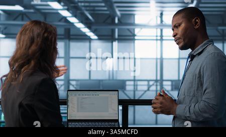 Teamworking data center computer scientists using artificial intelligence on laptop and tablet. Server room coworkers using neural networks AI on devices to do computing processes, camera A Stock Photo