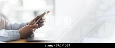 Woman hands holding smartphone and using laptop Stock Photo