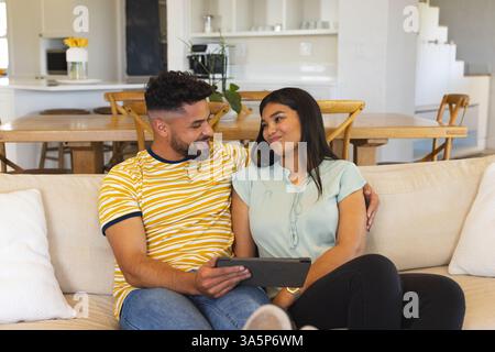 Couple relaxing on sofa, using tablet and sharing warm moment at home Stock Photo