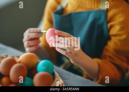 Woman is painting eggs. Happy family preparing for Easter. Stock Photo