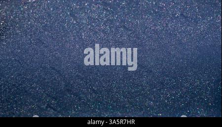 Shimmering fluid. Glitter surface. Gray silver violet defocused flow paint sparkling metal particles spill. Glossy stream texture abstract background. Stock Photo